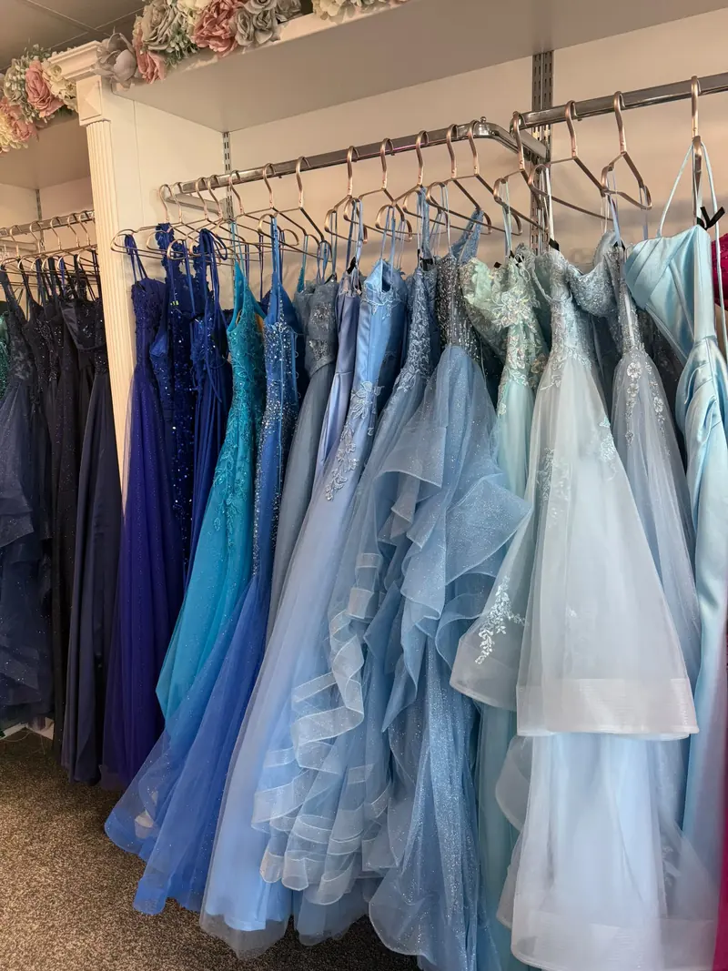 A rail of blue prom dresses, running from midnight navy and sapphire through cornflower and powder blue to pale ice tulle