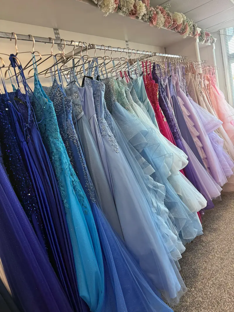 A rail of prom dresses running from sequinned navy and cobalt through turquoise and ice blue into lilac and blush tulle