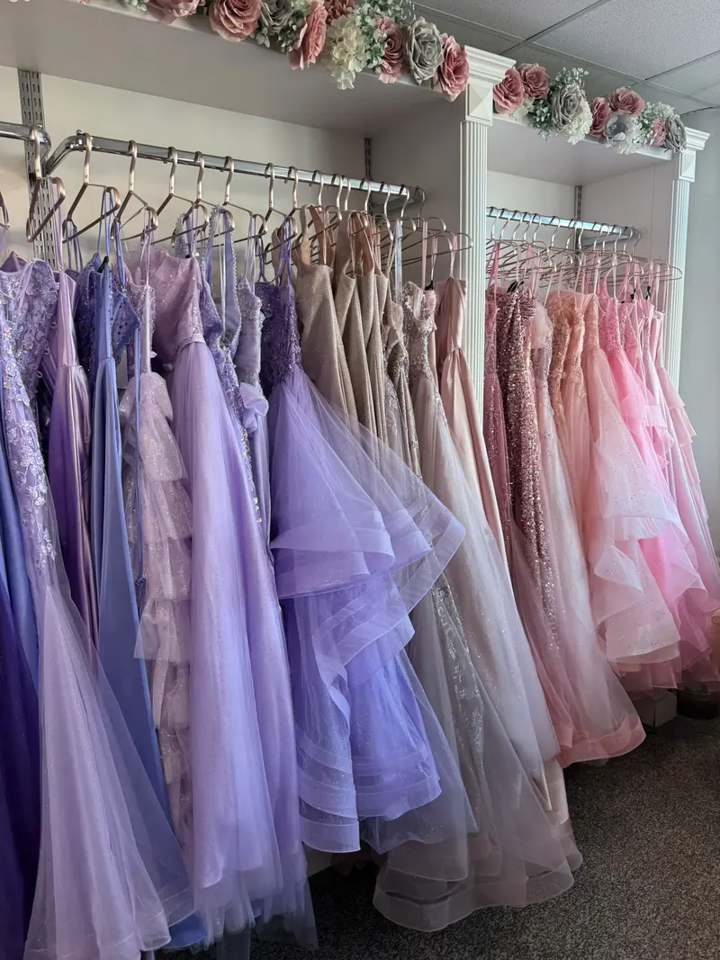 Lilac and lavender tiered tulle prom gowns beside champagne, rose gold and pink dresses on the boutique rails