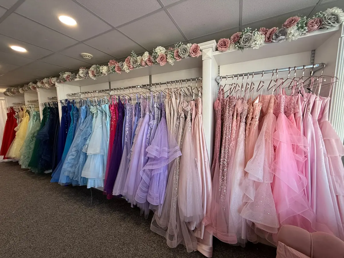 The full shop floor at The Prom Collection in Cleveleys, with rails of prom dresses running the length of the room from red and yellow through green, teal and blue to lilac and pink