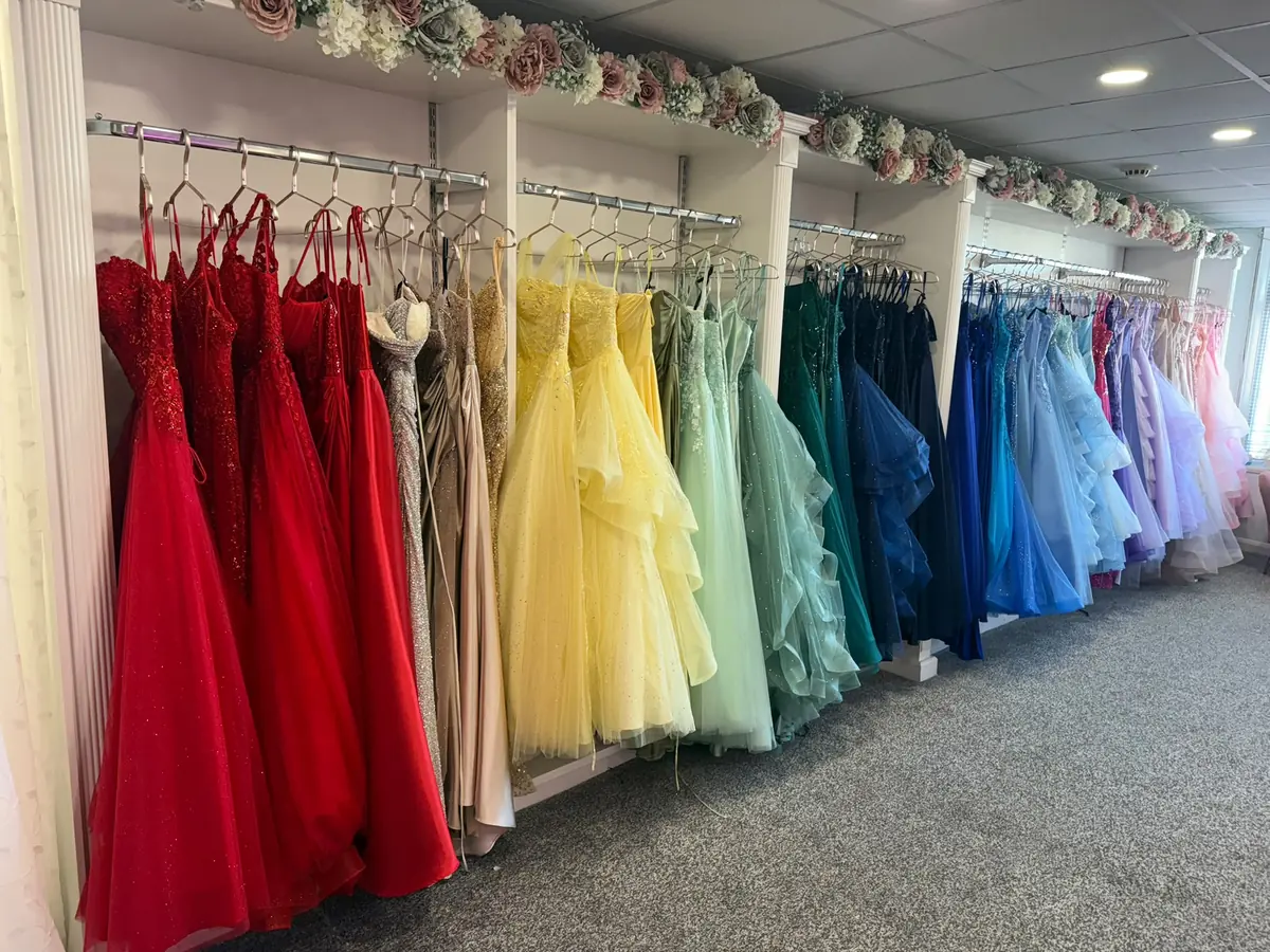 The main shop floor at The Prom Collection in Cleveleys, with prom dresses hung in colour order from red and gold through yellow, green and teal to blue, lilac and pink
